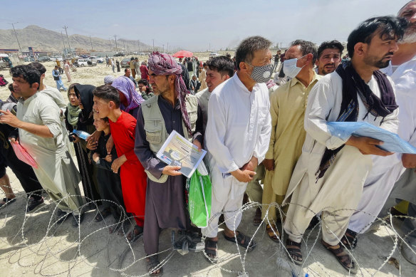 Hundreds queue outside Kabul’s airport with their documents hoping to be admitted.