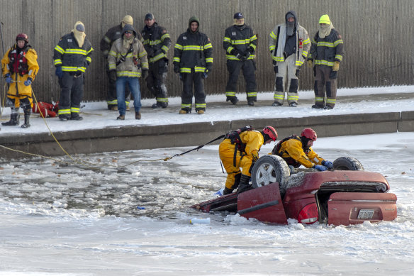 Kansas City Fire Department rescue workers are working to recover a minivan that has fallen into a creek.