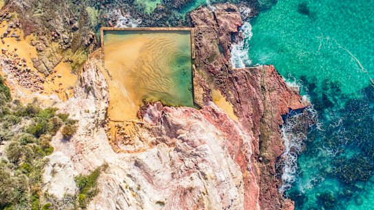 Aslings Beach in Eden features a rock pool framed by pink and white cliffs.