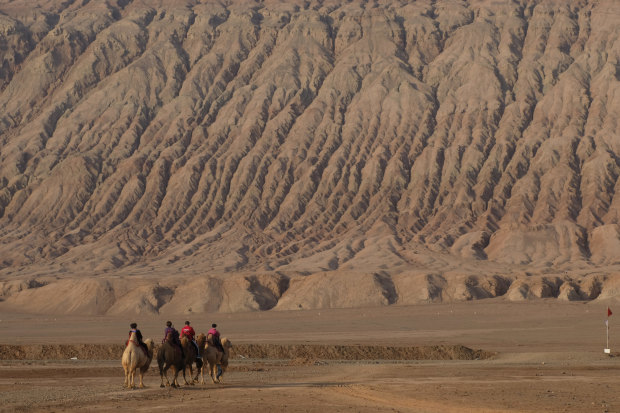 Tourists on camels at the Flaming Mountains in Turpan.