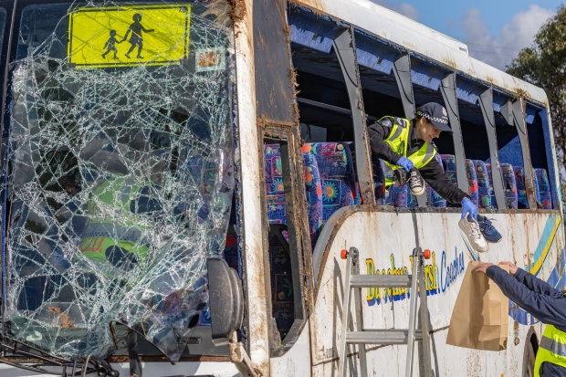 Police remove children’s shoes and belongings from the wreckage after the bus was righted the following day.