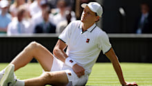 Jannik Sinner lays on the turf after taking a fall.