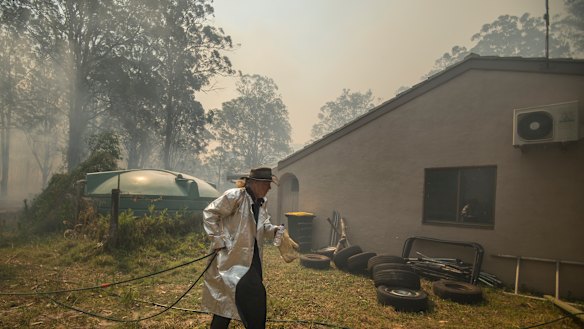 Mr Silver tries to protect his home from the advancing flames on Sunday.