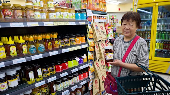 Beijing resident Ms. Yuan, 71, buys a jar of honey at Jingkelong Supermarket in Beijing. She says it improves her constipation.