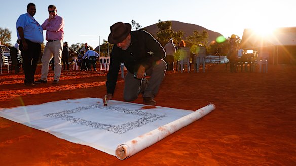 Noel Pearson signs a canvas on which the Uluru Statement from the Heart was later painted in May 2017.