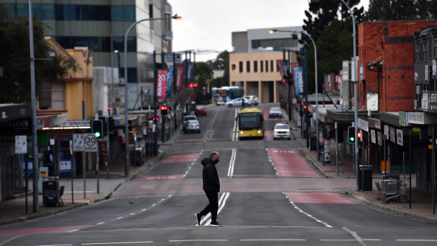 A lone person walks across Moore Street, Liverpool as Sydney bunkers down under tightened restrictions. 