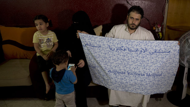 Aisha al-Lulu's father Waseem holds the hospital bed sheet his deceased daughter was covered with when she was sent home from a Jerusalem hospital.