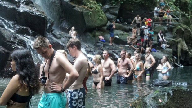 Tourists line up for photos under the Kato Lampo waterfall in Gianyar, Bali. 