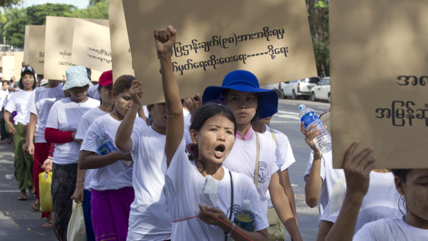 Myanmar workers holding a placard that reads "Government to sign 98 facts of ILO law," shout slogans on May 1, demanding workers' rights.