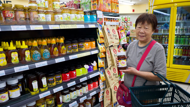Beijing resident Ms. Yuan, 71, buys a jar of honey at Jingkelong Supermarket in Beijing. She says it improves her constipation.