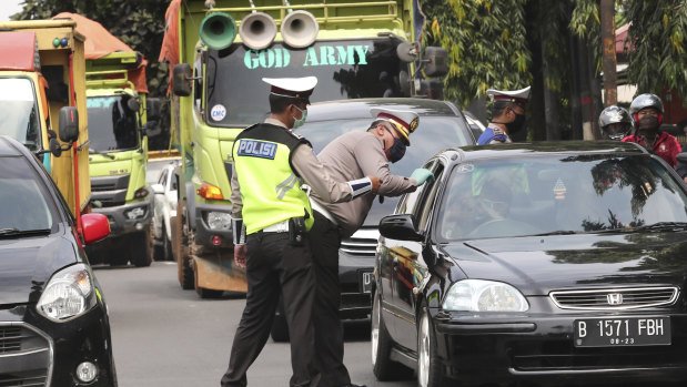 Police officers check the number of people seated inside a car during the imposition of large-scale social restriction, at a checkpoint in Jakarta, Indonesia, on Friday.