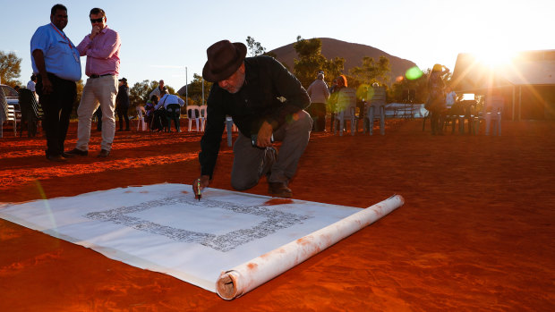 Noel Pearson signs a canvas on which the Uluru Statement from the Heart was later painted in May 2017.