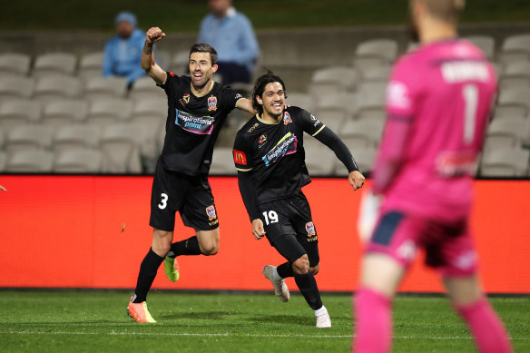 Kosta Petratos celebrates his late, late match-winner with Jets teammate Jason Hoffman as Sydney FC goalkeeper Andrew Redmayne rues an opportunity lost.