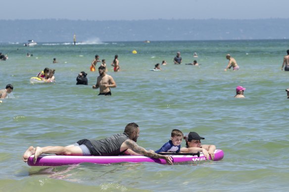 Adriana, Spase and their 4 year old son Milan playing on a paddleboard at Chelsea Beach in Melbourne’s South East. They’re from Doreen. Sunday 15th December 2024