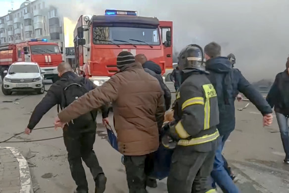 Rescuers and people carry a wounded person after shelling in Belgorod, Russia.