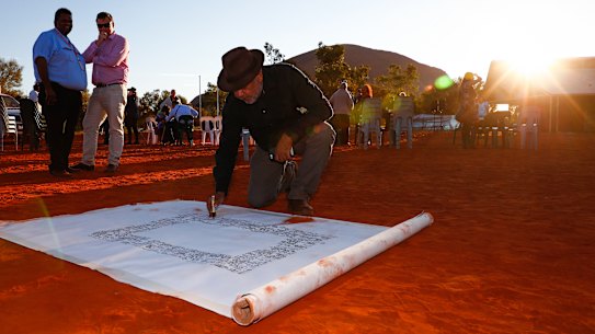 Noel Pearson signs a canvas on which the Uluru Statement from the Heart, which included the proposal for a Voice to Parliament, was later painted in May 2017.