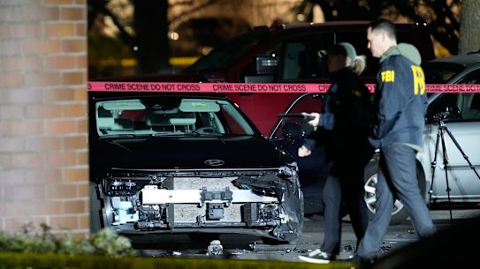 A damaged car is seen as law enforcement officials work the scene following reports that federal immigration officers shot and wounded people in Portland