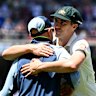 Pat Cummins hugs injured teammate Nathan Lyon while Travis Head waits to do the same after Australia’s win in the third Ashes Test in Adelaide.