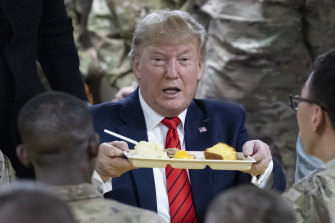 Trump  holds up a tray of Thanksgiving dinner during a surprise visit to Afghanistan.