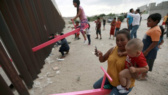 A mother and her baby play on a seesaw installed between the US and Mexico.