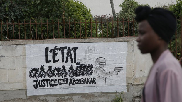 A woman passes by a poster that reads, "the state kills, justice for Aboubakar", referring to a driver who was shot by police two days ago in Nantes, western France.