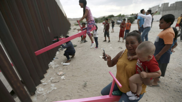 A mother and her baby play on a seesaw installed between the US and Mexico.