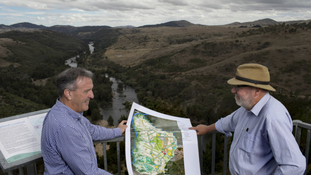 Riverview director David Maxwell, left, and consultant Tony Adam, at Shepherd's Lookout looking over the Murrumbidgee River and the area to the right to be developed for 11,500 homes and a conservation corridor. The pair, photographed in 2017, hold the development plan.