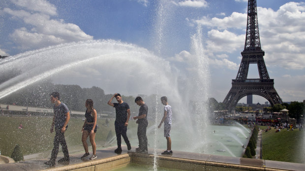 People cool off as they walk along the fountain of Warsaw near Eiffel Tower in Paris, on Wednesday.