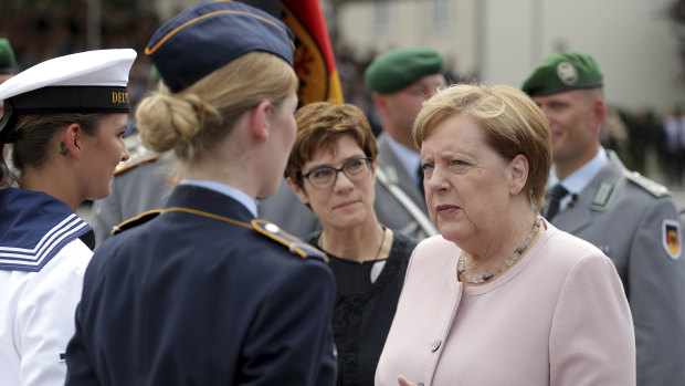 German Chancellor Angela Merkel and German Defence Minister Annegret Kramp-Karrenbauer, front second right, talk to soldiers during the ceremony in Berlin.