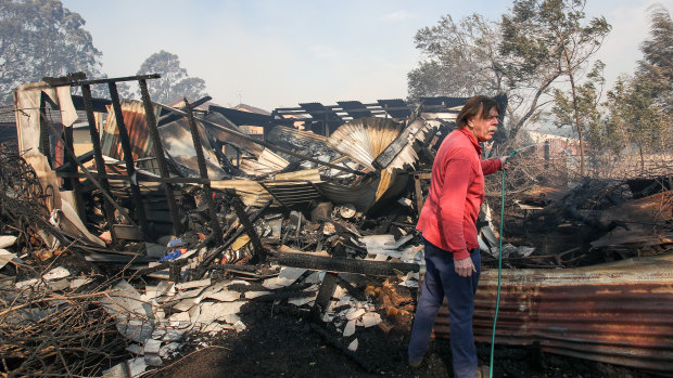 A resident hoses down a shed destroyed by the fire at Bomaderry. 