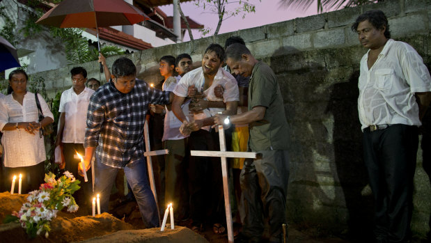 Relatives place flowers after the burial of three victims of the same family, who died at Easter Sunday bomb blast at St. Sebastian Church in Negombo, Sri Lanka.