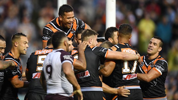 Wests Tigers players celebrate after Robbie Farah's match-sealing try in the opening round of the 2019 season, which Lawrence watched from home.