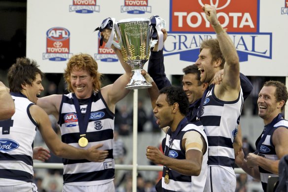 Cats players celebrate their team’s win over the Magpies in the Grand Final on the podium.