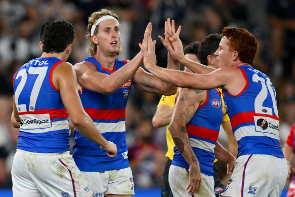 Aaron Naughton congratulated by his Bulldogs team mates after kicking a goal.
