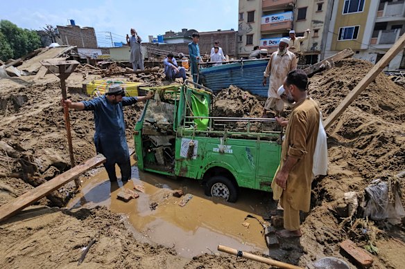 Residents remove mud to recover a rickshaw from debris after flash flooding in Mingora in Pakistan’s north-west.