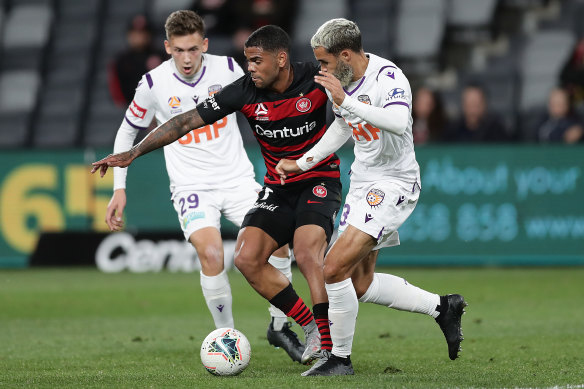 Western Sydney Wanderers forward Kwame Yeboah squeezes through two Perth Glory opponents.