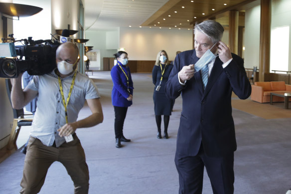 Finance Minister Mathias Cormann puts his mask back on after addressing the media.