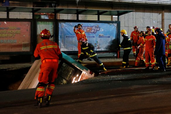 Rescue workers try to reach people in the bus, which plunged into the sinkhole.