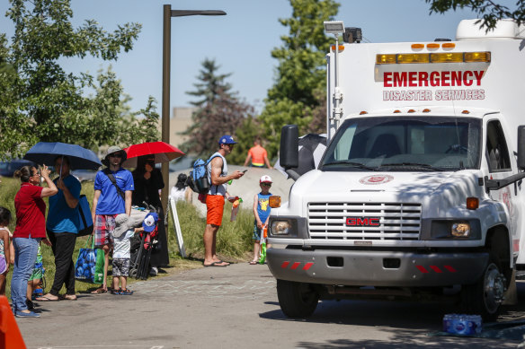 A Salvation Army vehicle is setup as a cooling station as people line up to get into a splash park to beat the heat in Calgary, Alberta.