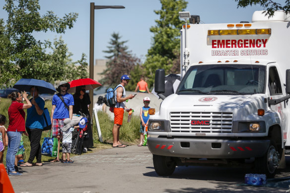 A Salvation Army vehicle is setup as a cooling station as people line up to get into a splash park to beat the heat in Calgary, Alberta.