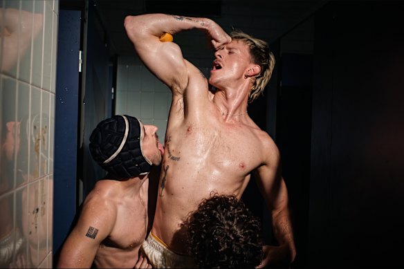 Rising Australian pop singer ANDY squeezing an orange wedge between his bicep and forearm. 