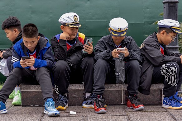 Young Chinese tourists in Russian sailors caps next to the S-56, a replica of Stalinets-class submarine of the Soviet Navya in Vladivostok.