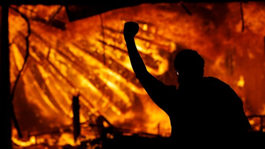A protester gestures in front of the burning third precinct building of the Minneapolis Police Department on Thursday.