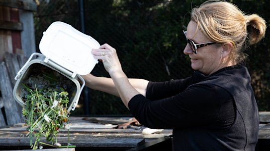 Marika Nabung empties her compost bin into the large compost at a community garden in Rose Bay,