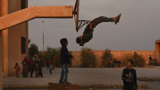 A child shows off his gymnastics skills at a high school full of people fleeing the fighting at the Syria-Turkey border.