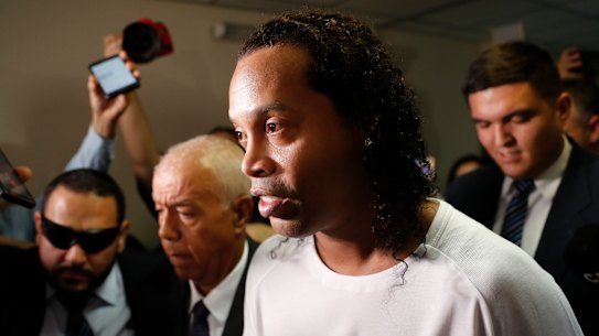Former soccer star Ronaldinho is escorted by police. 