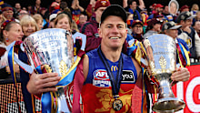 Dayne Zorko of the Lions reacts holding two AFL Premiership Cups.