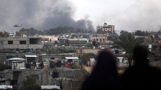 Palestinians watch an Israeli helicopter fly over Khan Younis, Gaza Strip.