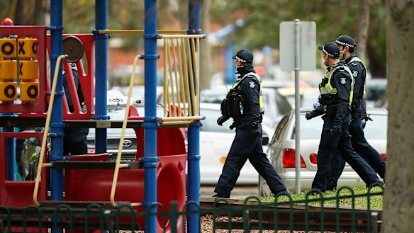 A police patrol walks past a playground in Melbourne.