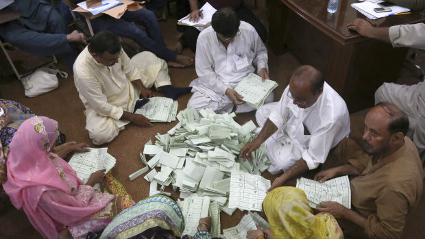 Pakistani election staff count the votes after polls closed in Karachi.